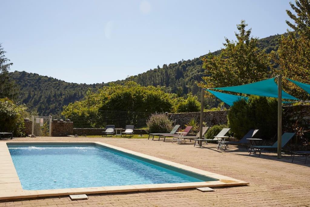 - une piscine avec des chaises et un parasol bleu dans l'établissement Gîte de 4 ou 5 personnes la Draille, à Gravières