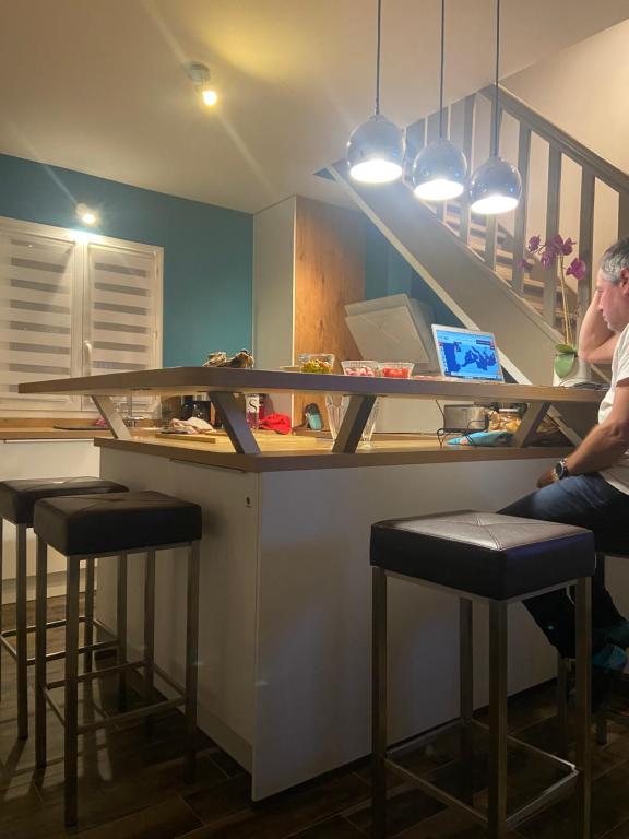 un homme assis à un bar avec un comptoir et des tabourets dans l'établissement Maison mer piscine Cargese à 1 heure d'Ajaccio, à Cargèse