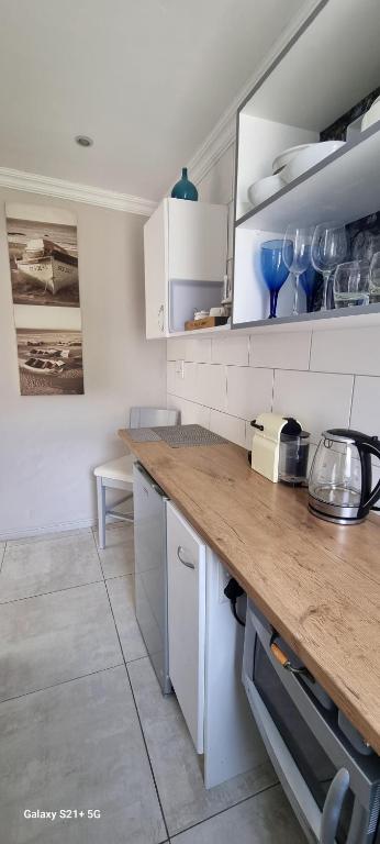 a kitchen with white cabinets and a wooden counter top at Studio on Albert, Hout Bay in Hout Bay