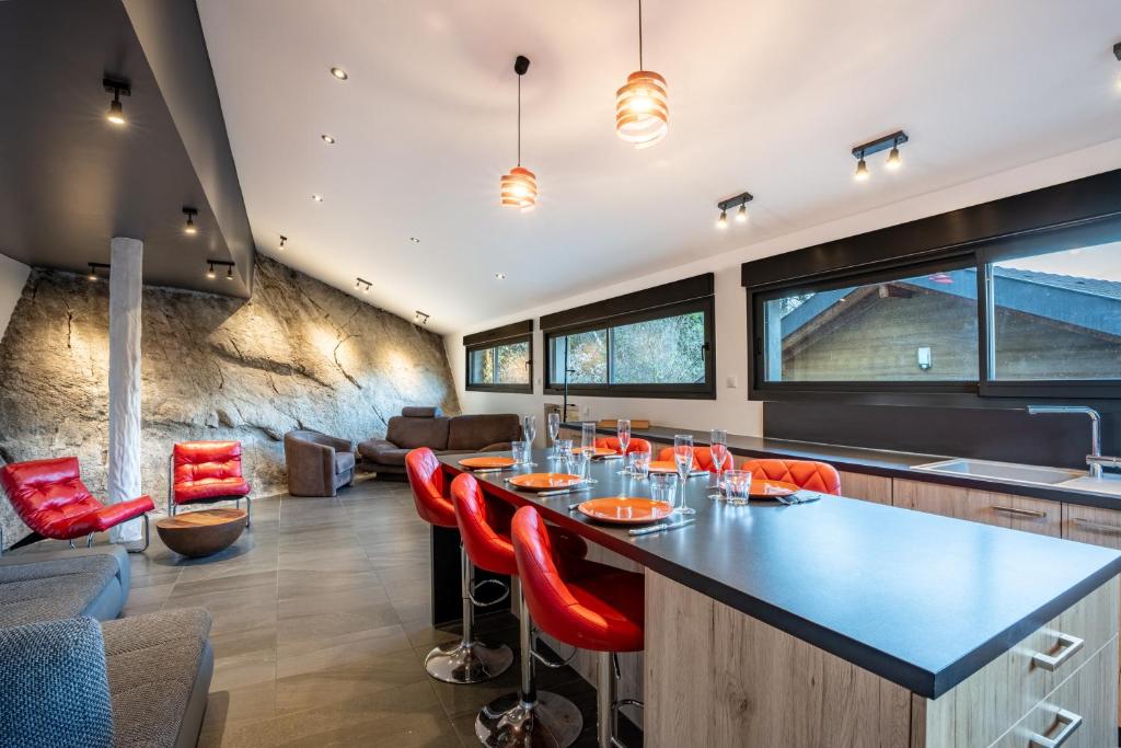 une cuisine ouverte avec un bar et des chaises rouges dans l'établissement La Verrière du Lac, à Sévrier
