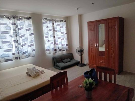 a living room with a bed and a table and a chair at Amaia Steps Capitol Condo in Bacolod
