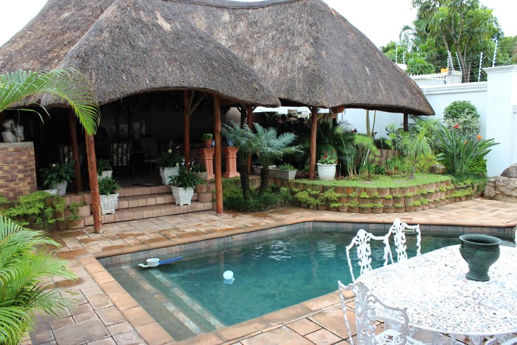a small swimming pool with a thatch roof at Almost Heaven in Durban