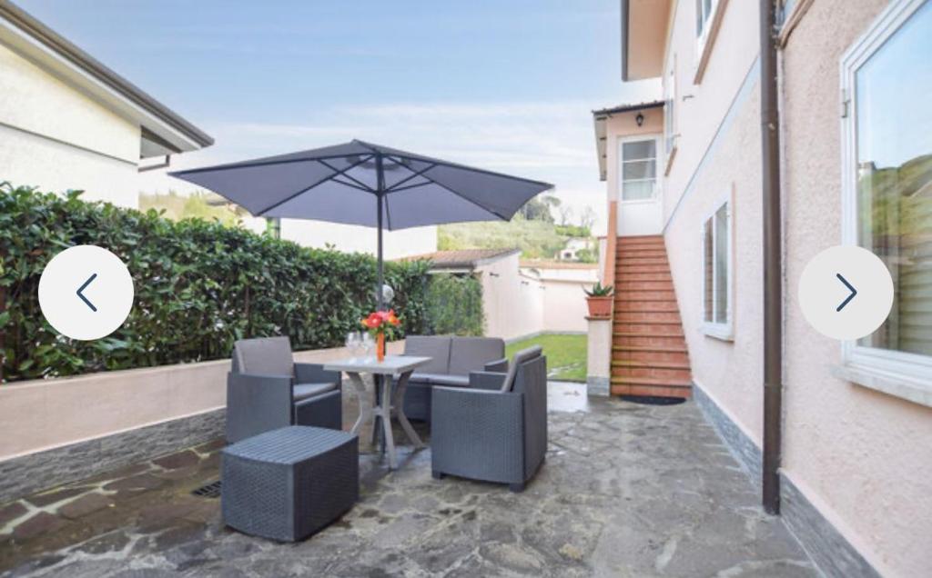a patio with a table and chairs and an umbrella at Casa Martina in Camaiore