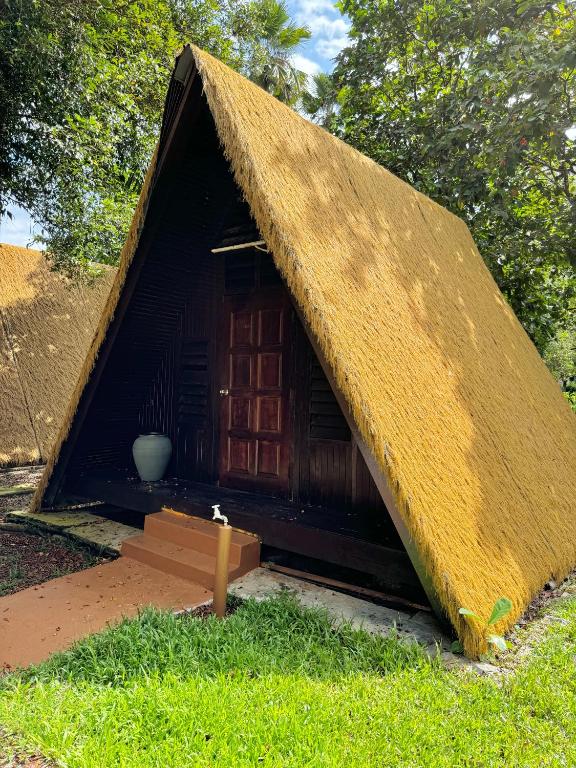 a small house with a thatch roof on the grass at Chalet Kuala Woh Resort in Tapah