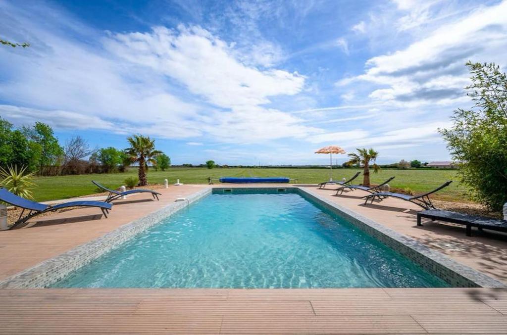 a swimming pool with several chairs and an umbrella at Vacation rental with pool and Jacuzzi, close to Arles - sleeps 10 in Arles