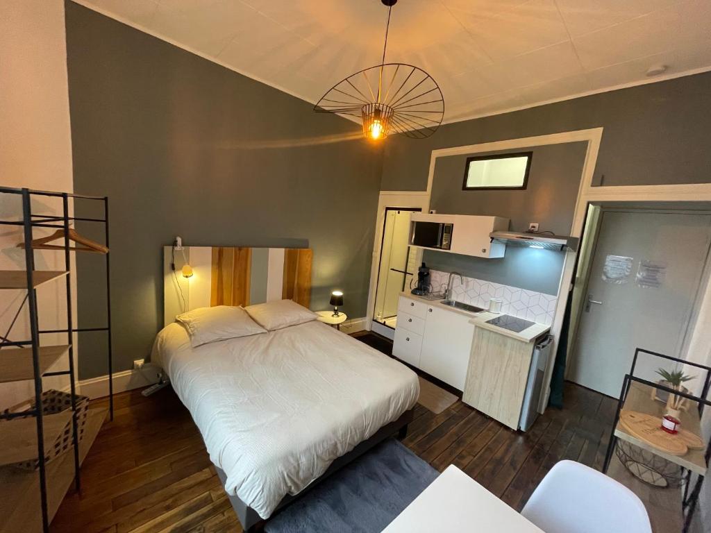 une chambre avec un grand lit et une cuisine dans l'établissement Rubis 1, à Vichy