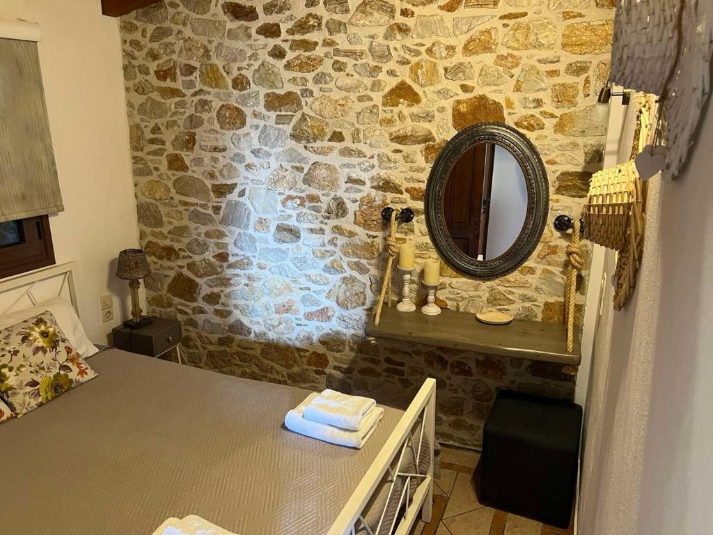 a bathroom with a mirror on a stone wall at Villa Maraki in Agia Paraskevi