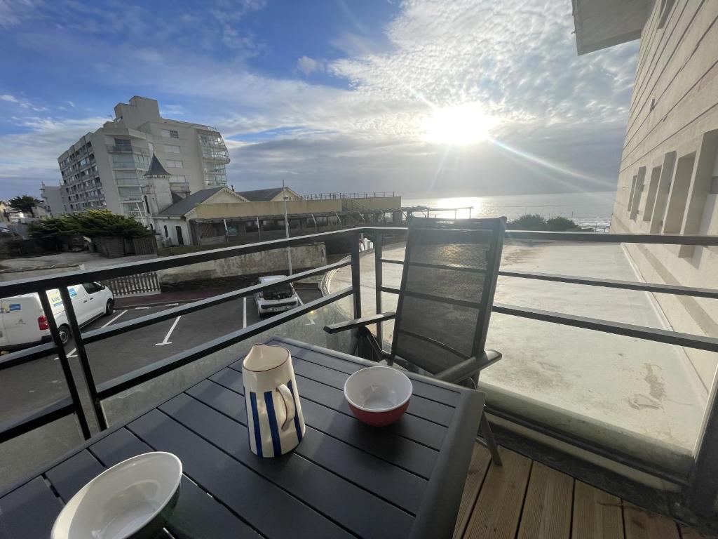 une table et des chaises sur un balcon avec vue sur l'eau dans l'établissement La Rose des Sables, à Saint-Gilles-Croix-de-Vie
