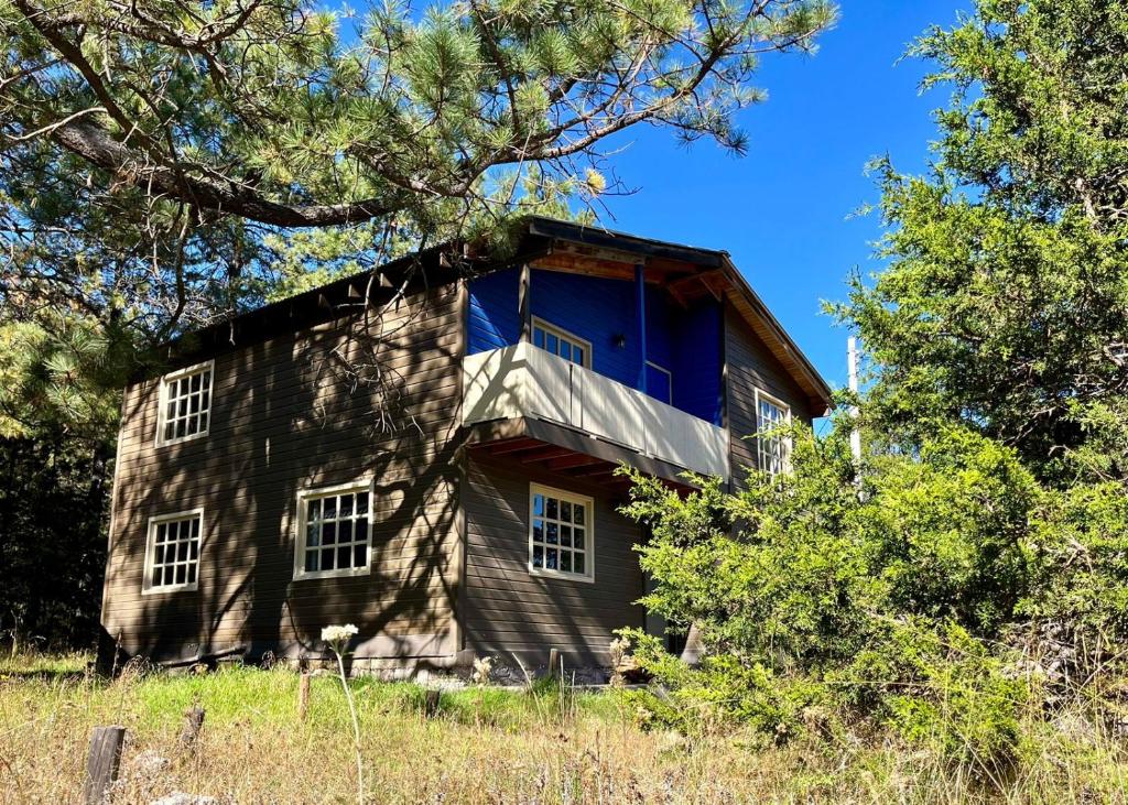 an old house with a blue window on the side of it at Encantadora Cabaña del Lago - Parque La Pirámide in La Florida