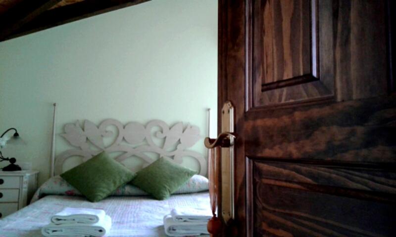 una camera da letto con un letto con cuscini verdi e una porta in legno di El llagar de Mestas De Con a Con