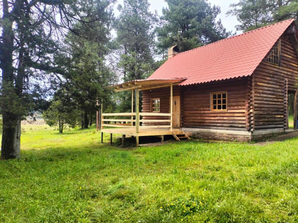 a log cabin with a red roof in a field at Hermosa Cabaña de Montaña - Parque La Pirámide in Las Adjuntas
