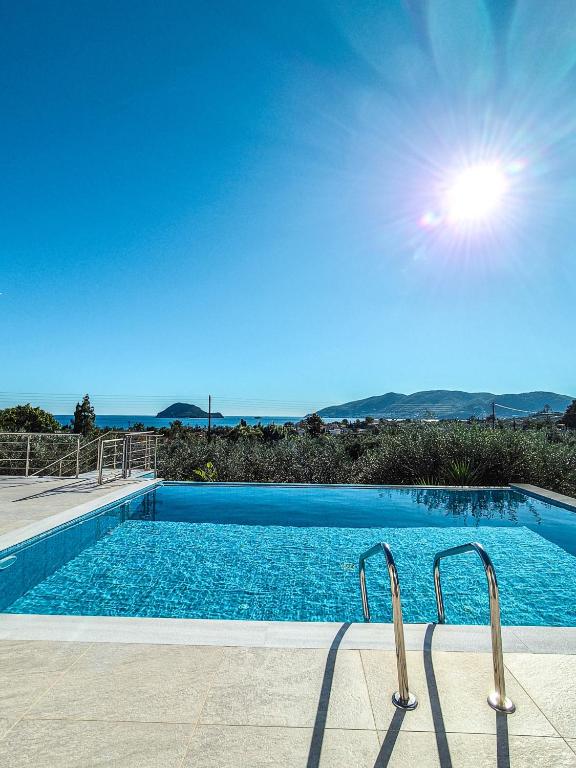 a swimming pool with the sun in the sky at Villa Símera in Laganas