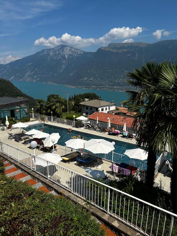 a swimming pool with umbrellas and a view of the water at Piccola Italia Residence - Tremosine sul Garda in Tremosine Sul Garda