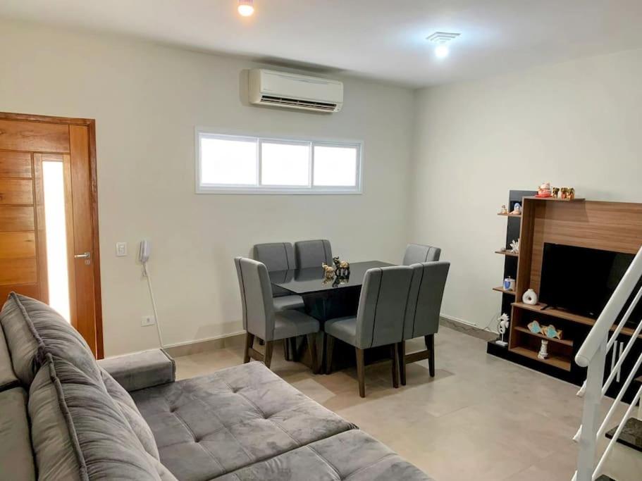 a living room with a table and chairs and a couch at Triplex em Caraguatatuba! Alto padrão in Caraguatatuba