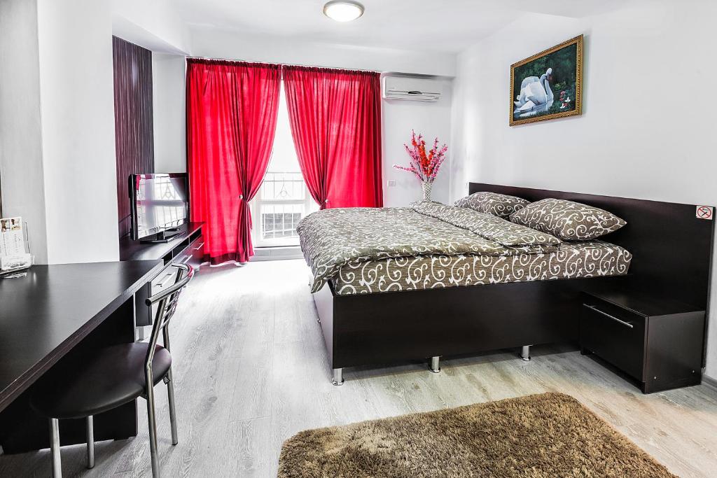 a bedroom with a bed and a desk and red curtains at HomeService Apartments on Stefan cel Mare boulevard in Chişinău