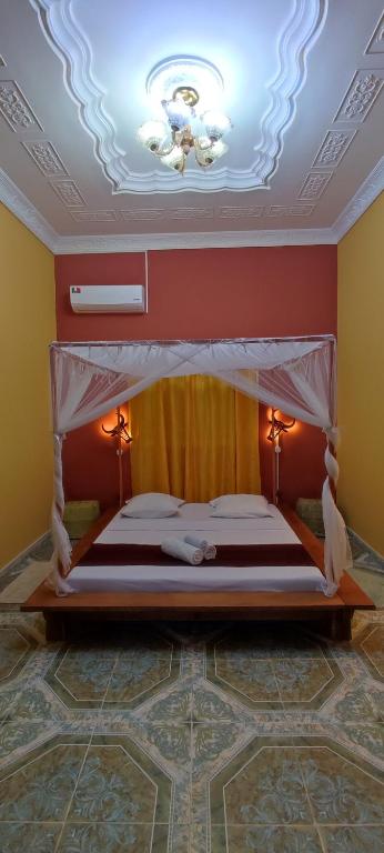 a bedroom with a large bed with a ceiling at Le DIEGO Hôtel in Antsiranana
