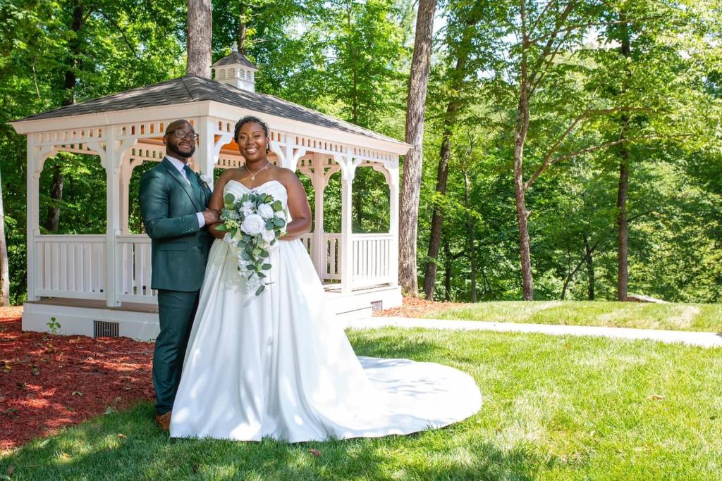 een bruid en bruidegom staan voor een prieel bij Whisper Chateau Weddings Reunions Groups 75 Plus in Greensboro