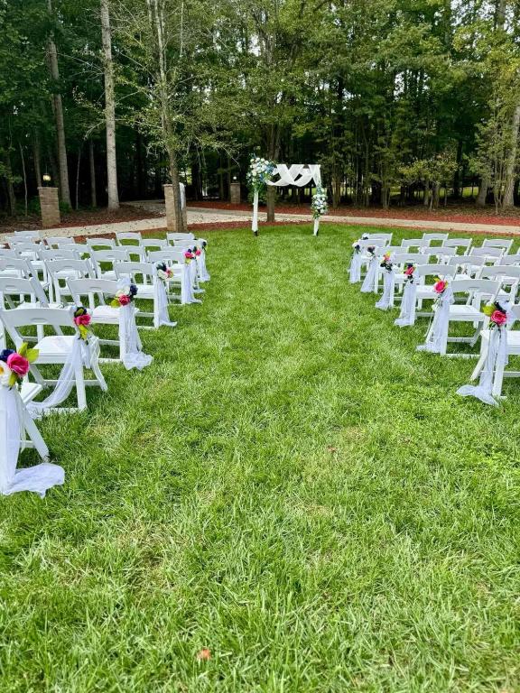 a row of white chairs sitting in the grass at Whisper Chateau Weddings Reunions Groups 75 Plus in Greensboro
