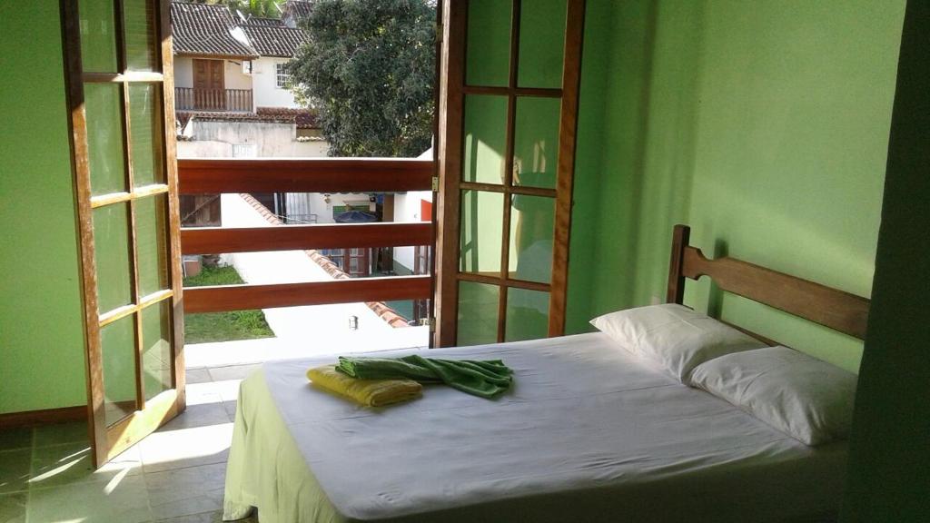 a bed in a room with a large window at Aconchego in Paraty