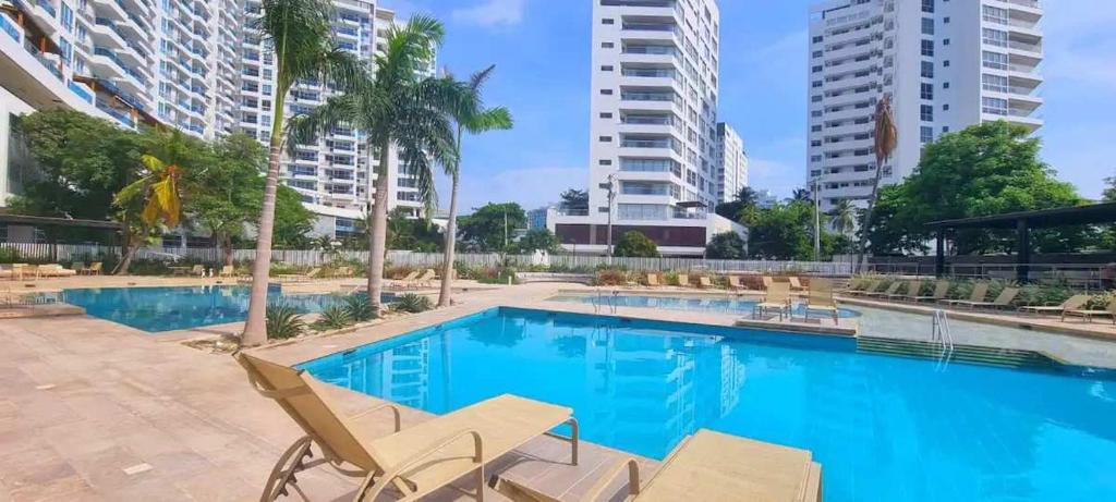 ein Pool mit zwei Stühlen und zwei hohen Gebäuden in der Unterkunft Majestic 3BR with Fantastic Pool in Bolivar in Gaira