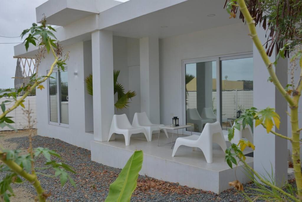 a white house with white chairs and windows at Casa Daan, 5 minutes from the beach in Noord