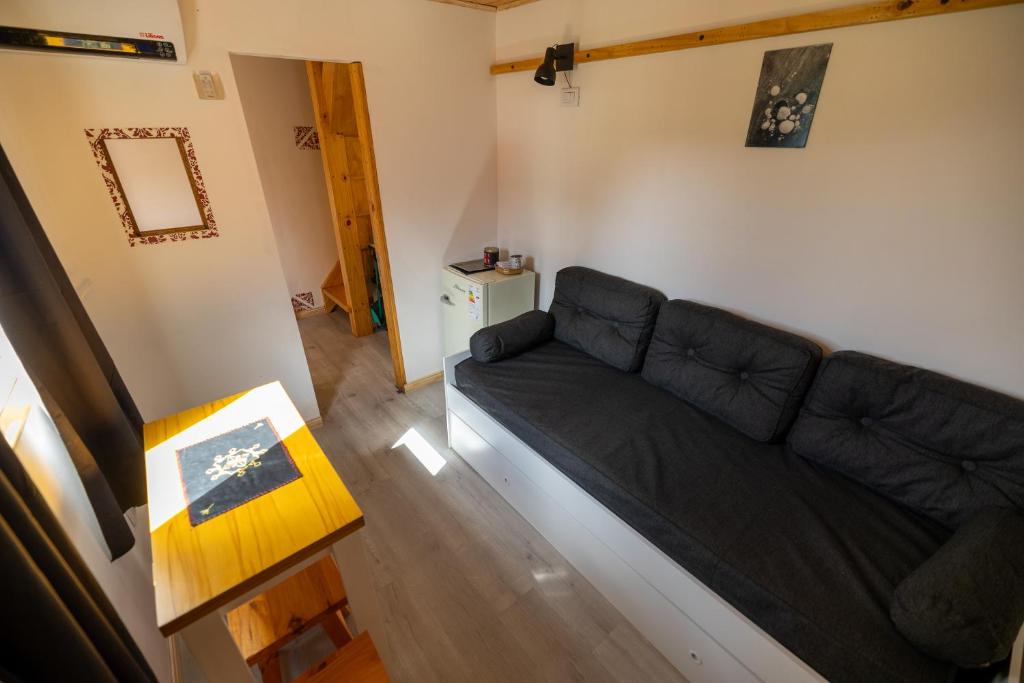 a living room with a black couch and a table at Mistico Hostel 23 in El Chalten