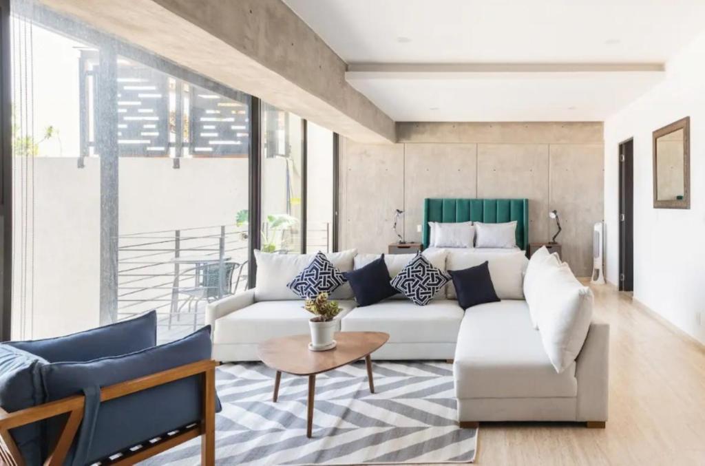 ein Wohnzimmer mit einer weißen Couch und einem Tisch in der Unterkunft CH604 1-1BR 1 BTH Deluxe in Mexiko-Stadt