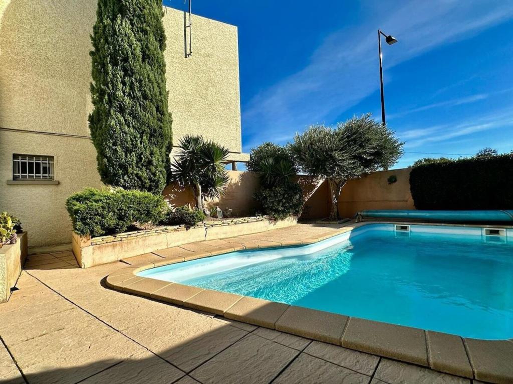 a swimming pool in front of a building with trees at Riba d'aude in Carcassonne