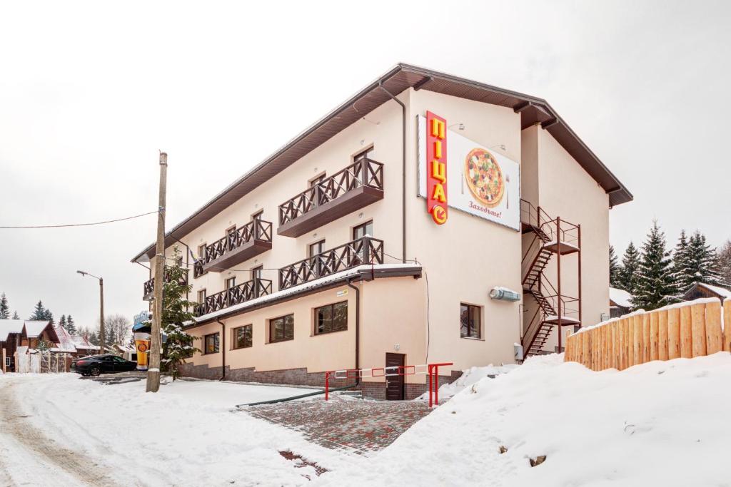 ヤブルニツァにあるSkilandhouse Yablunytsyaの雪中のピザ看板のある建物