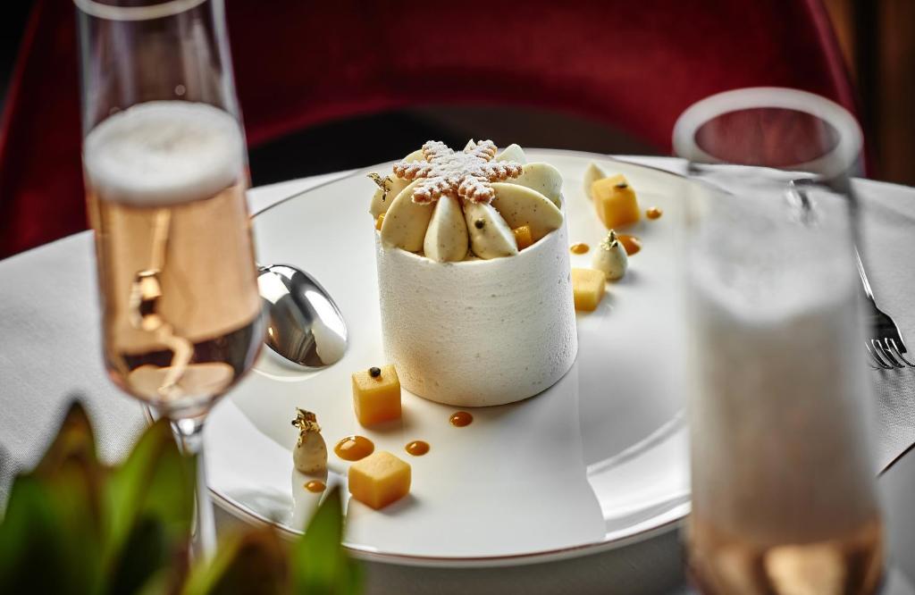 a dessert on a white plate with a glass of champagne at Apogée Courchevel, Oetker Hotels in Courchevel