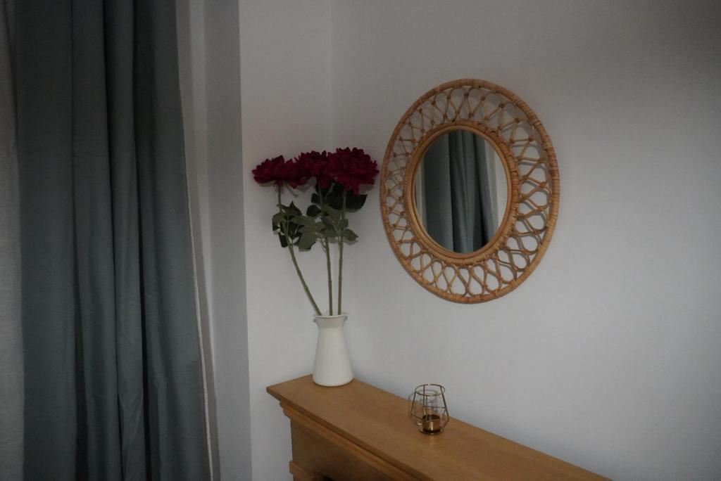 un vaso di fiori su un tavolo con uno specchio di Gabry Elle's Cozy Place - Calea Moșilor a Bucarest