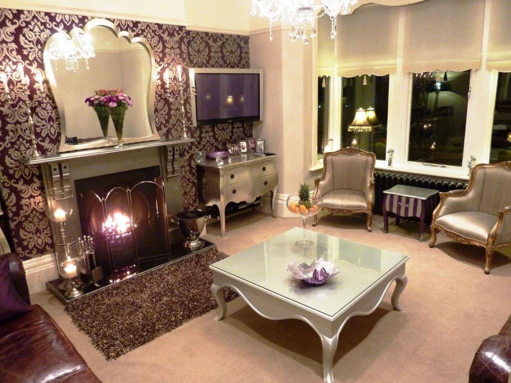 a living room with a fireplace and a table at Shelbourne House in Harrogate