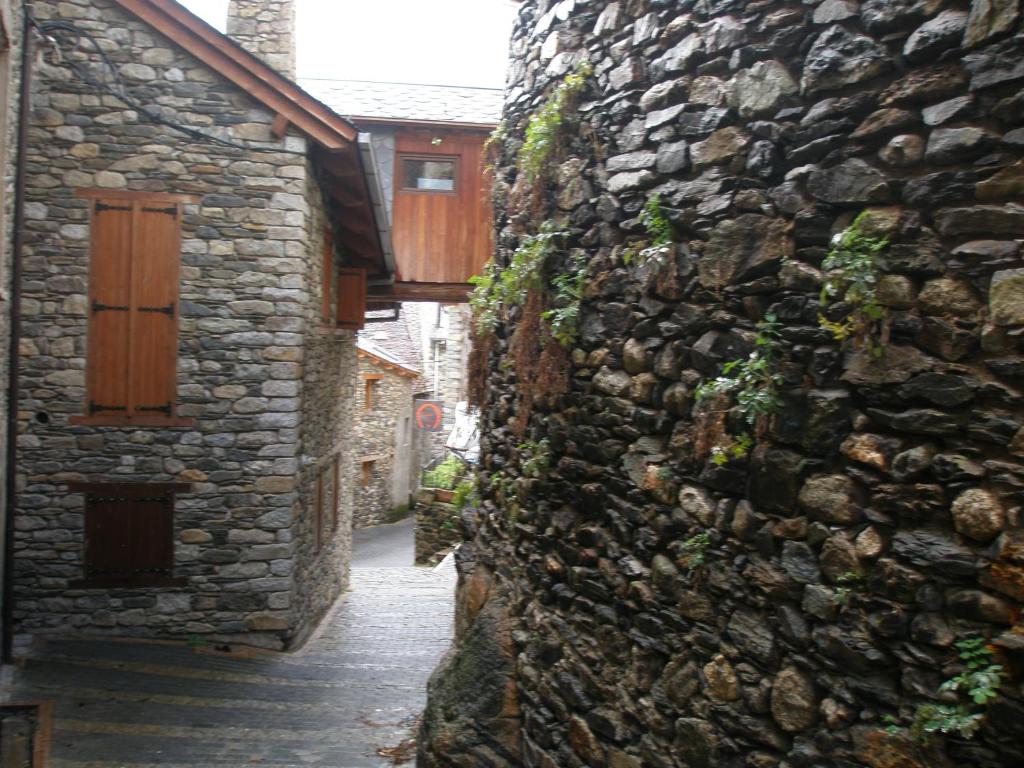 un callejón con una pared de piedra y una puerta de madera en Apartamentos Ca de Marti, en Bohí