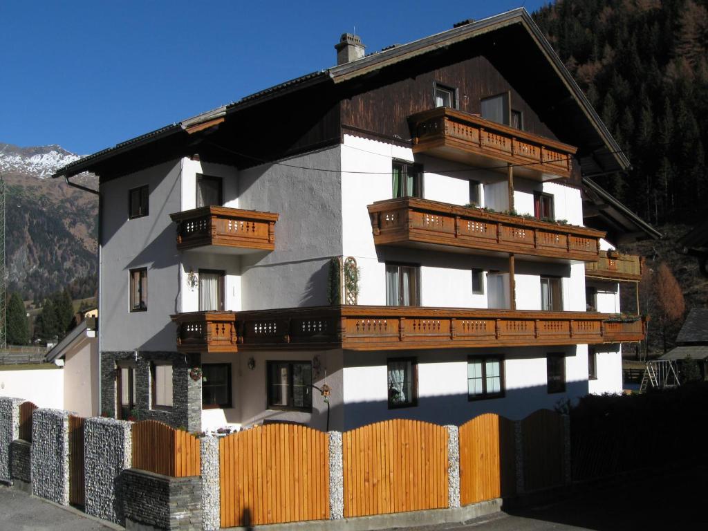 un edificio con balcones de madera y una valla en Appartements Schusser, en Mallnitz