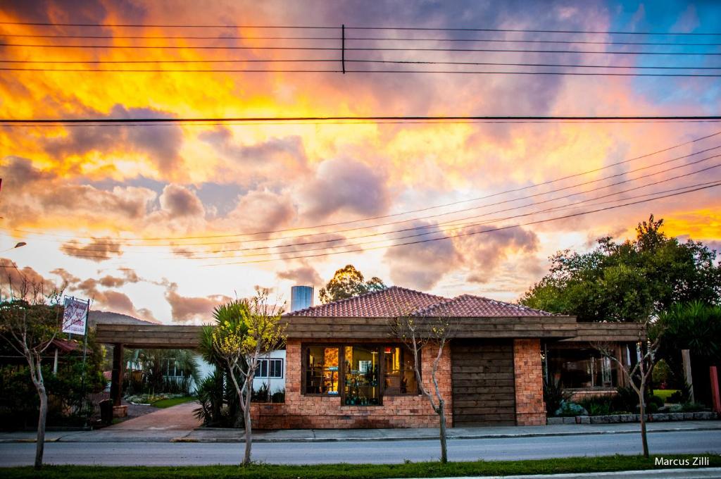 una casa frente a un cielo nublado al atardecer en Pousada das Flores UpSerra, en Urubici