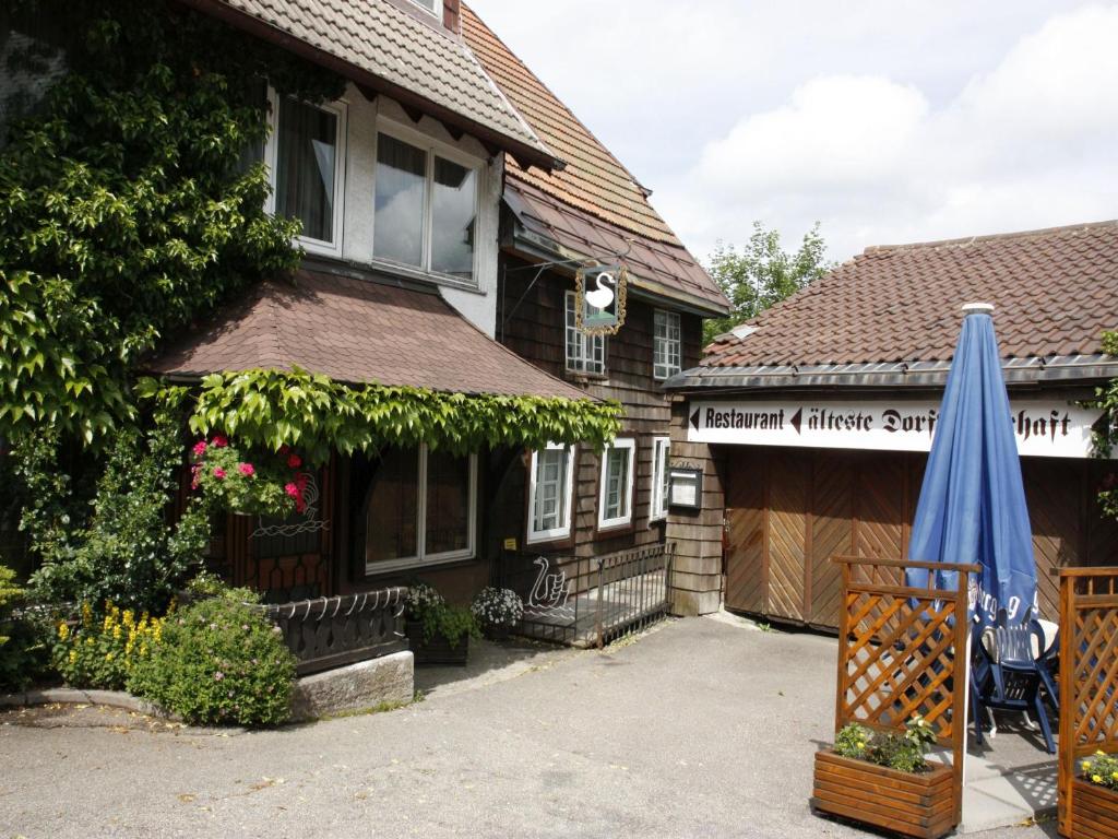 uma casa com um guarda-chuva em frente em Schwarzwaldgasthof Hotel Schwanen em Schonach