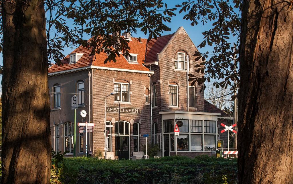 un grand bâtiment en briques avec un toit rouge dans l'établissement Hotel Station Amstelveen, à Amstelveen