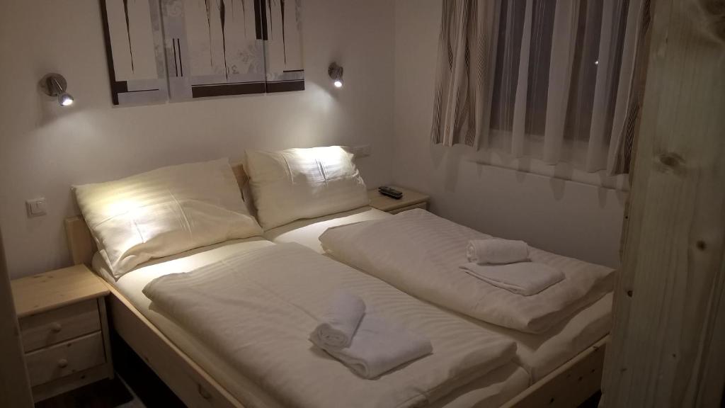 a bed with white sheets and two towels on it at Ferienhaus Dorfruhe in Sankt Stefan an der Gail