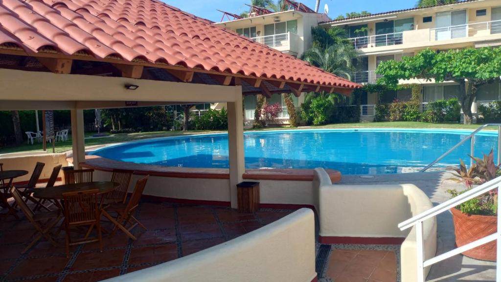 a swimming pool with a table and chairs next to a building at Condominio a pie de playa-Ixtapa in Ixtapa
