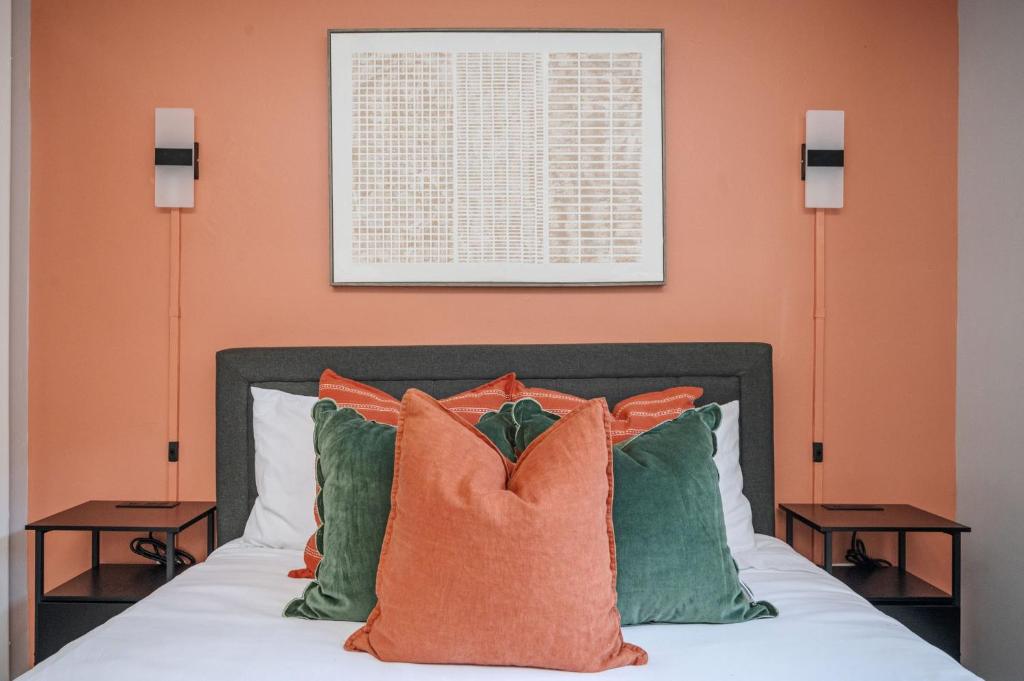 アトランタにあるThe Traveler's Retreat, 5 mins to airport and 15 mins to downtownのベッドルーム1室(オレンジ色の壁と枕が備わるベッド1台付)