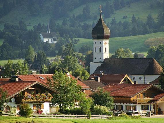 a small village with a church and a tower at FeWo Steckenbergblick/Gästecard in Unterammergau