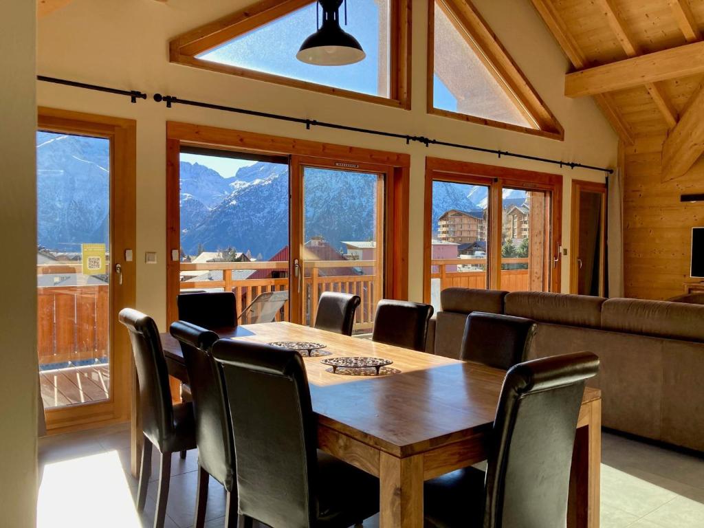 une salle à manger avec une table, des chaises et des fenêtres dans l'établissement Grand appart lumineux 7 pièces, 250m pistes, 10 pers, animaux admis - FR-1-811-13, à Les Deux Alpes