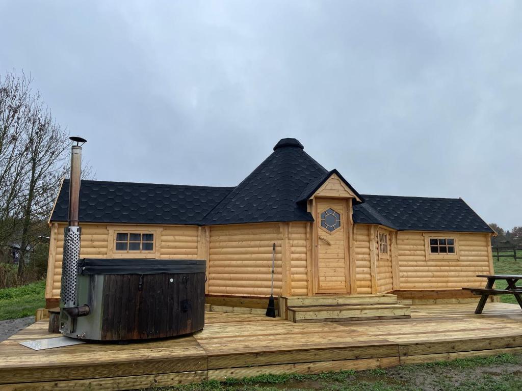 a large log cabin with a grill in front of it at Kota finlandais avec bain nordique privatif et ferme pédagogique - FR-1-410-457 in Cérans-Foulletourte