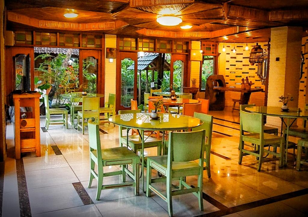 a restaurant with tables and chairs in a room at Arys Garden Hotel Yogyakarta in Yogyakarta