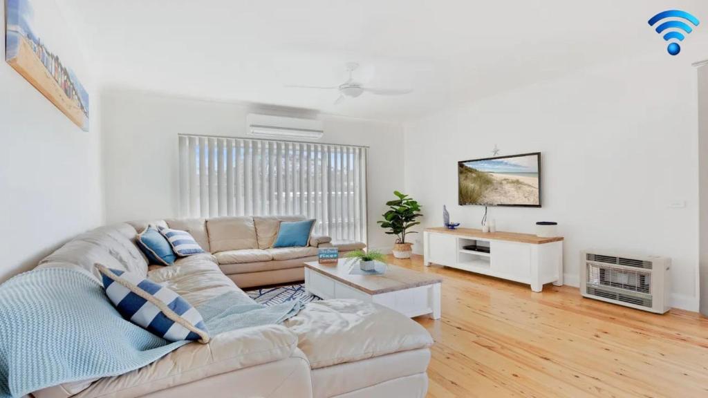 a living room with a couch and a tv at Sienna by the Sea in Callala Beach