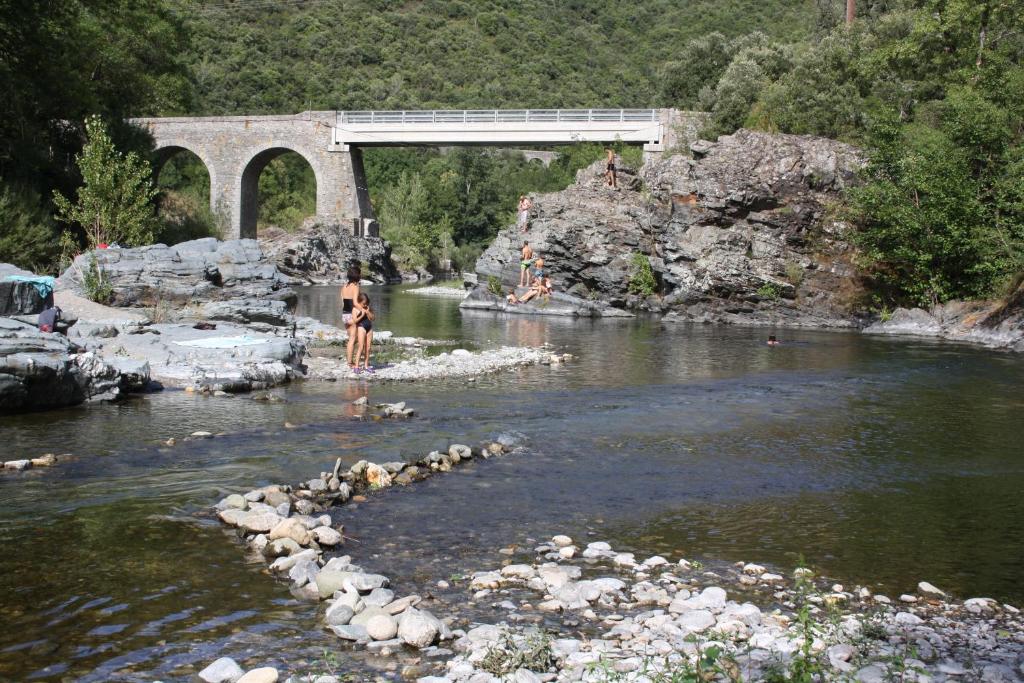 a person standing in the water under a bridge at Camping Les Gorges de l'Hérault in Sumène