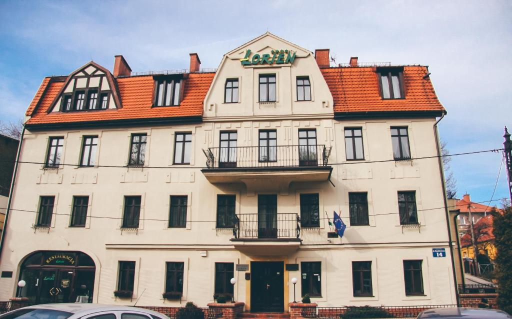 un gran edificio blanco con un cartel. en Pensjonat Lorien, en Szczawno-Zdrój