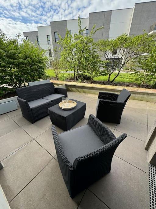 d'une terrasse avec des canapés, des chaises et une table. dans l'établissement Appartement spacieux avec terrasse, à Caen
