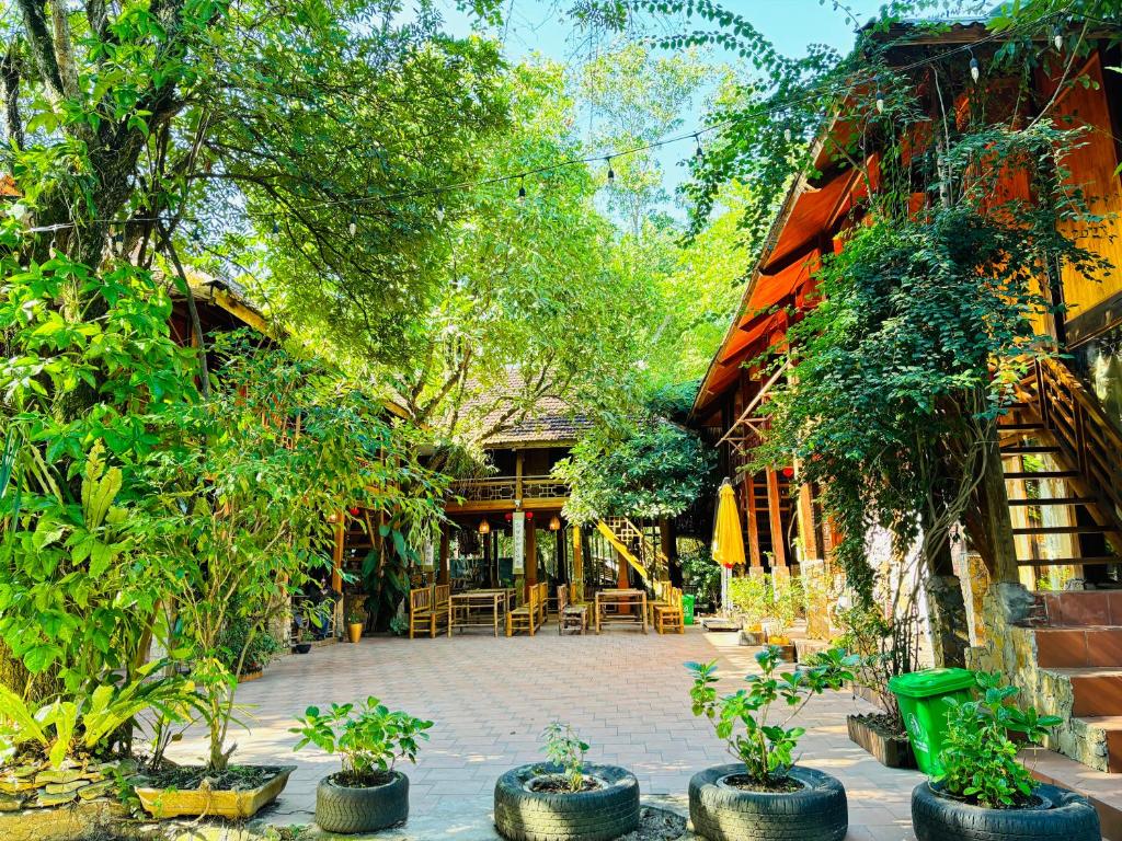 Un patio con sillas y árboles frente a un edificio. en Fairy House Mai Châu, en Mai Chau