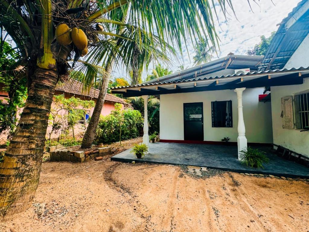 a house with a palm tree in front of it at Villa Vinuth Bliss in Mirissa